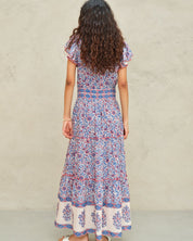 Back view of the tiered Mabe Apparel Della maxi dress in blue and pink artisan print on a model.