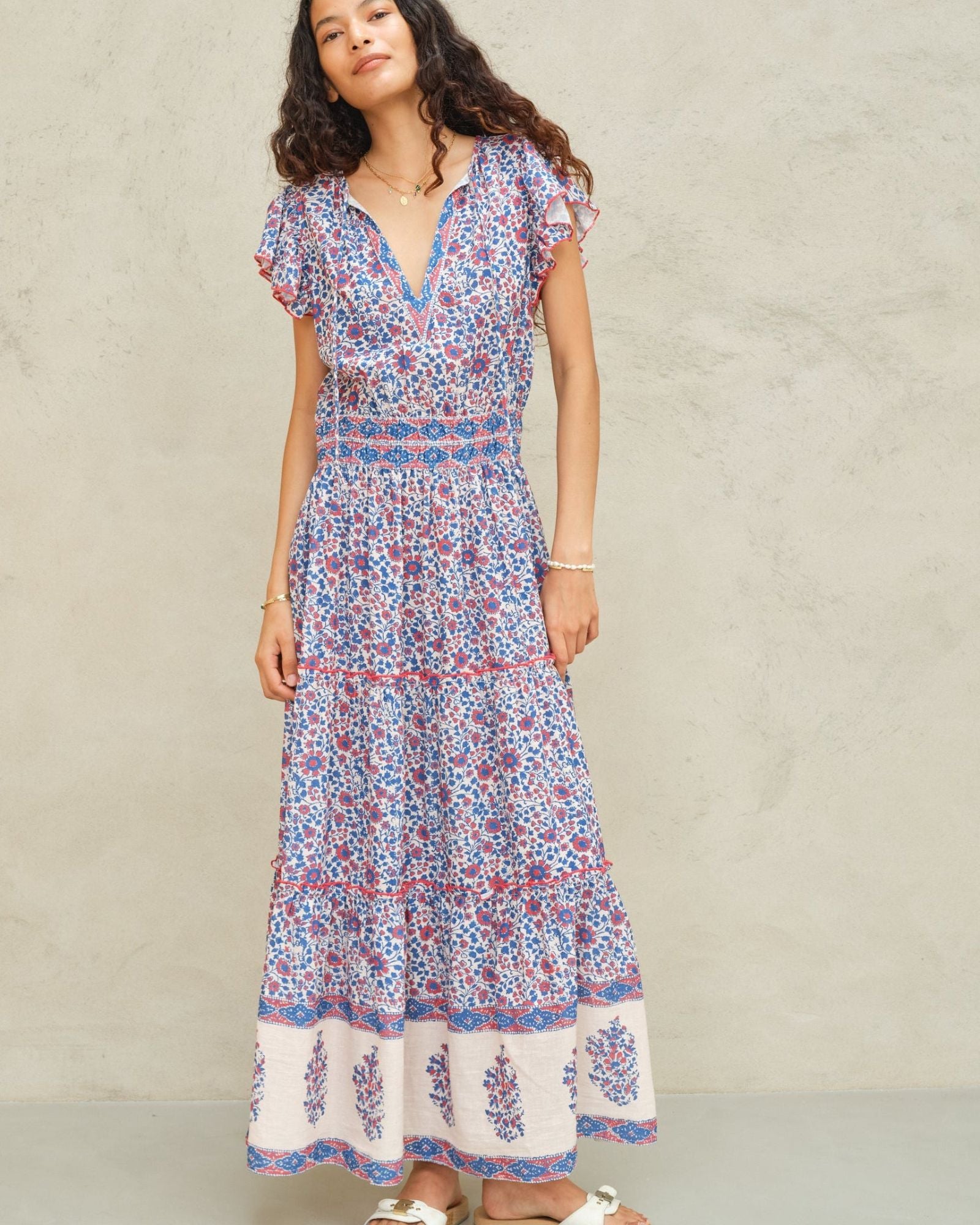 Woman wearing Mabe Apparel Della cotton maxi dress in blue and pink floral print with flutter sleeves.