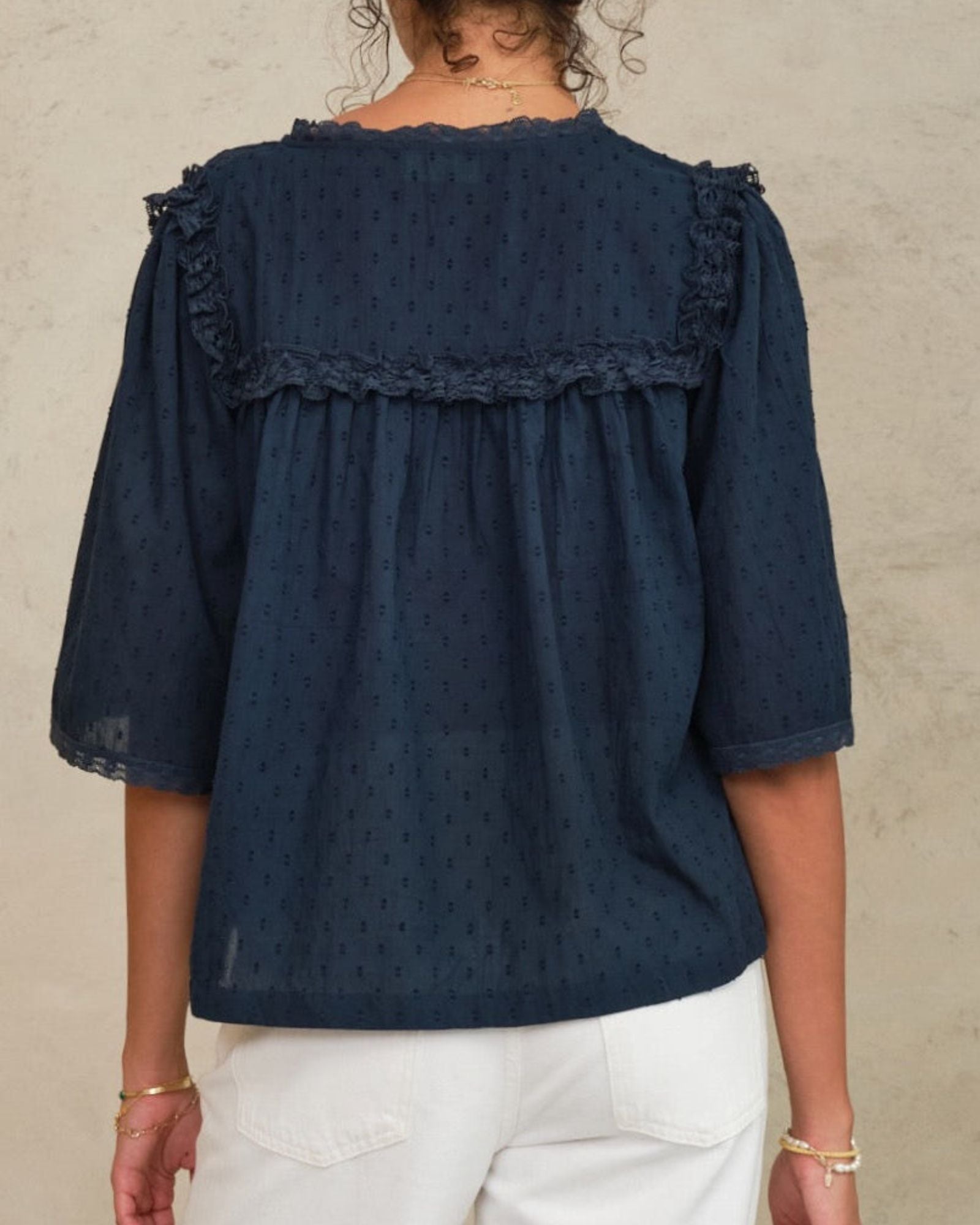 Back view of a woman wearing the Mabe Apparel navy blue embroidered blouse with wide sleeves.