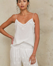 Model wearing a Mabe Apparel white embroidered strappy top paired with a matching tiered skirt.