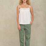 Model wearing a Mabe Apparel white lace camisole paired with green cuffed utility trousers.