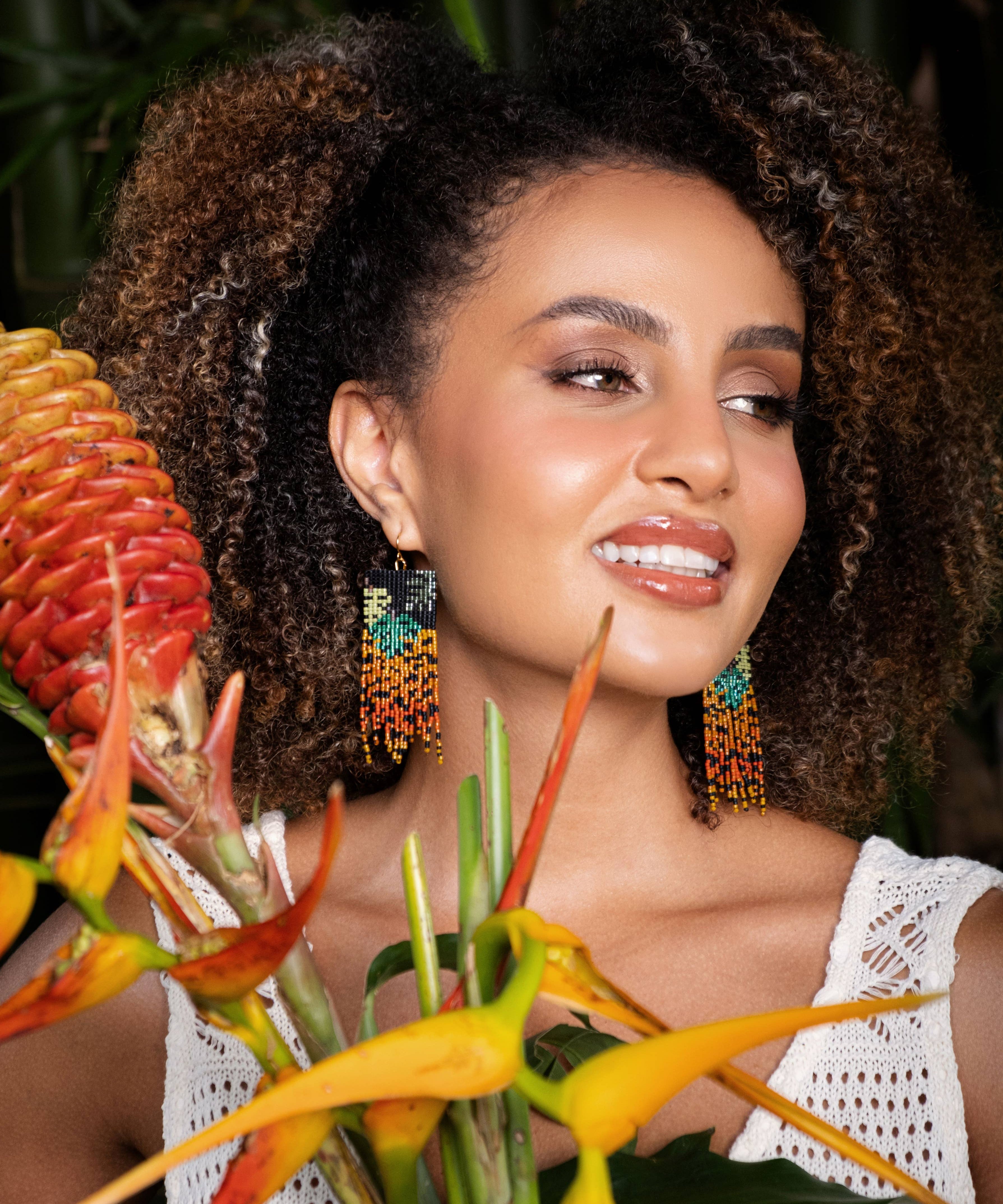 Woman wearing Mayana Designs Beaded Handwoven Jaguar Fringe Earrings, styled with a casual boho-chic outfit.