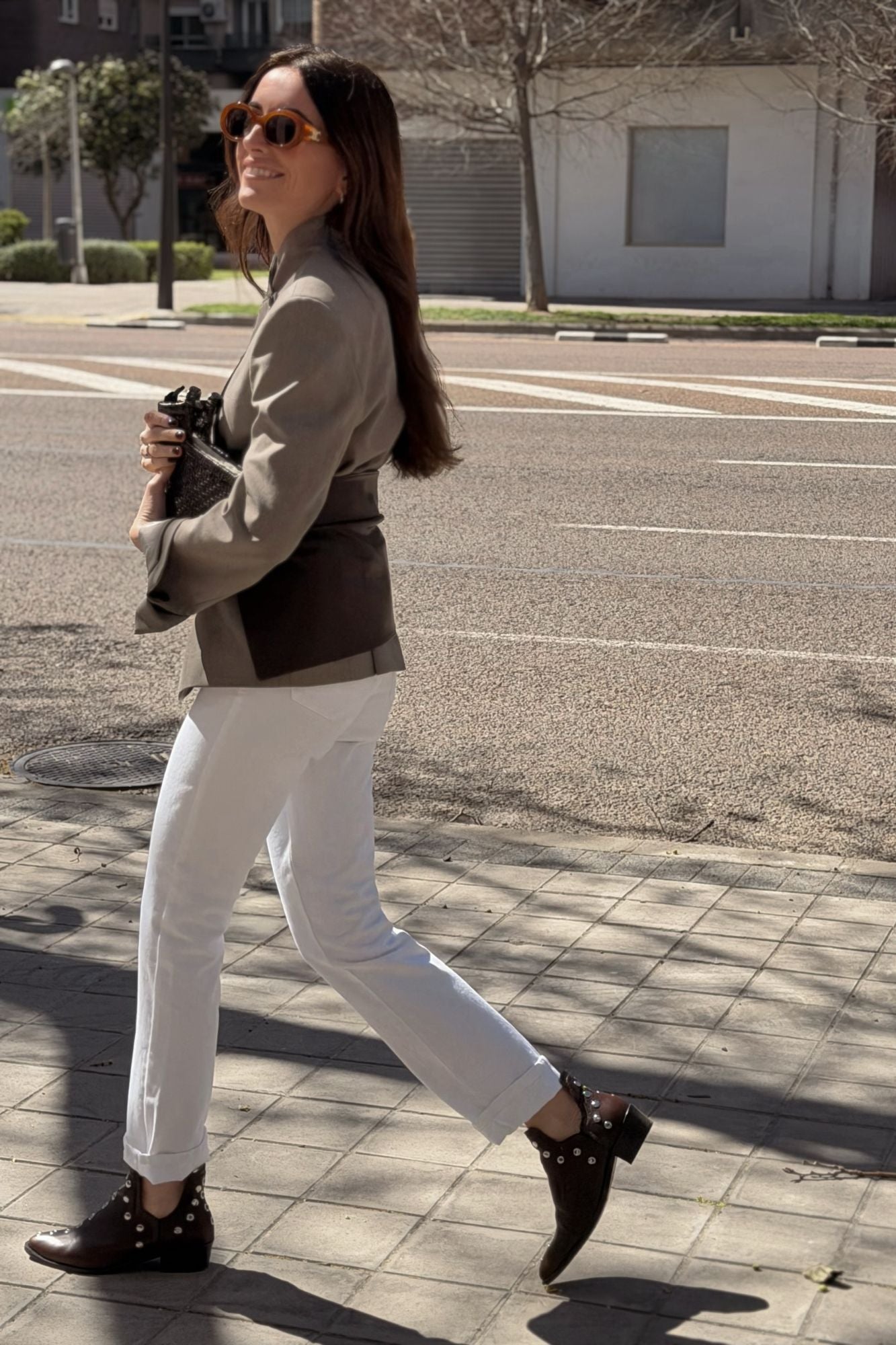 Woman walking in MICUIR Punky chocolate ankle boots with white jeans and a blazer