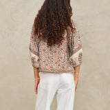 Back view of a model showcasing the fit of a cream and coral red printed block jacket by Mabe Apparel.
