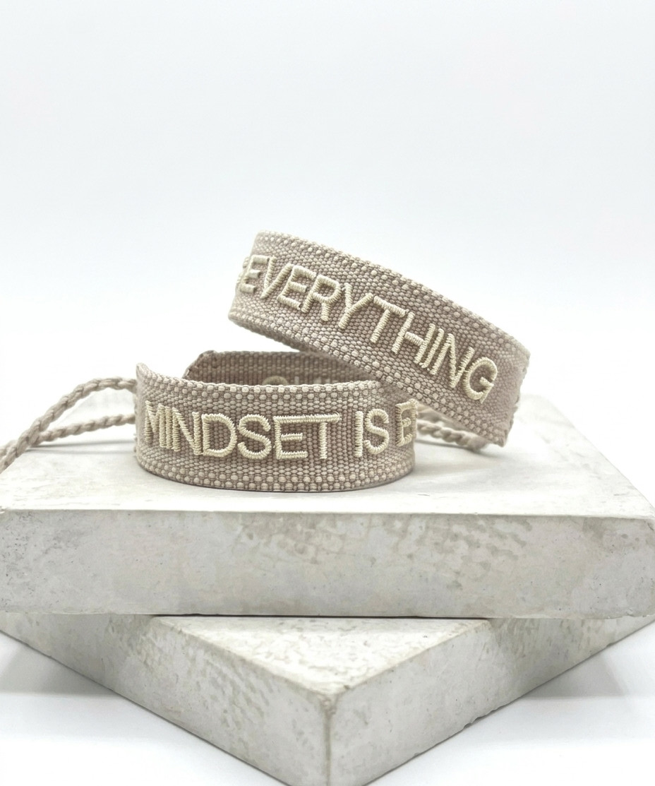 Close-up of adjustable woven statement bracelet with embroidered “MINDSET IS EVERYTHING” lettering and sliding knot tassel cords.