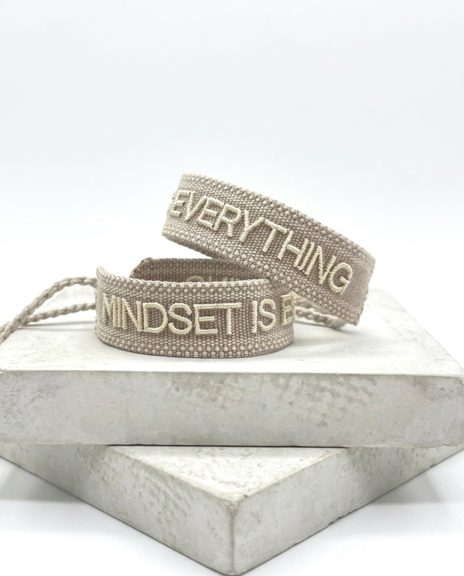 Close-up of adjustable woven statement bracelet with embroidered “MINDSET IS EVERYTHING” lettering and sliding knot tassel cords.