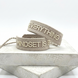Close-up of adjustable woven statement bracelet with embroidered “MINDSET IS EVERYTHING” lettering and sliding knot tassel cords.