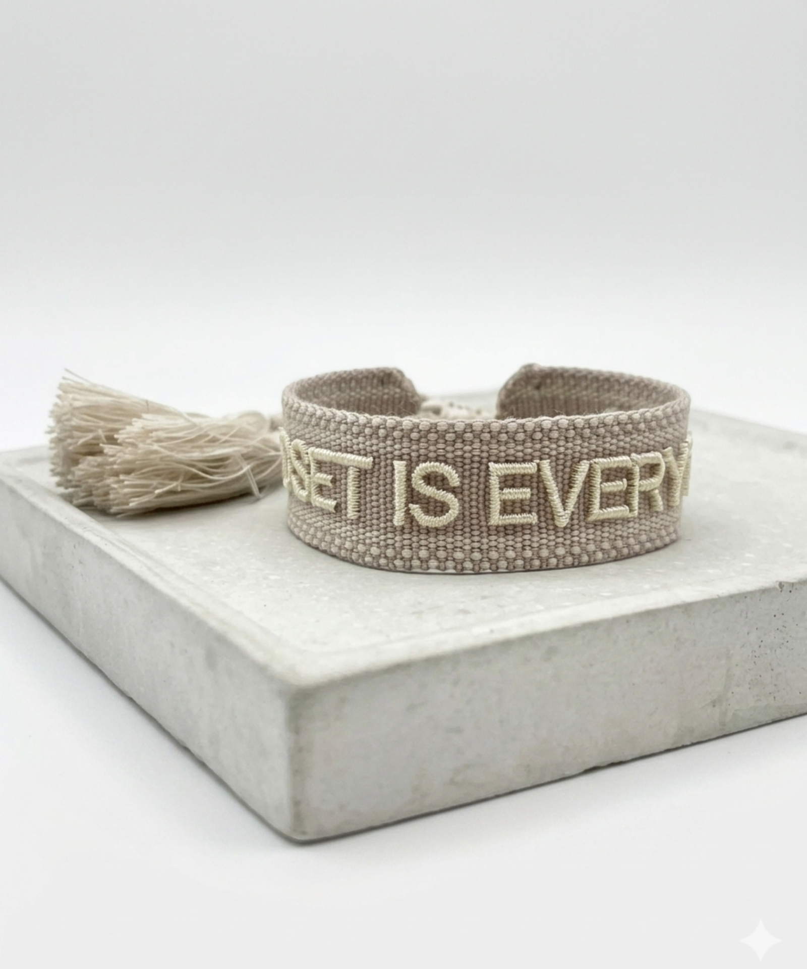 Close-up of adjustable woven statement bracelet with embroidered “MINDSET IS EVERYTHING” lettering and sliding knot tassel cords.