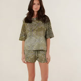 A model wearing the oversized khaki green bandana print Henry T-Shirt, featuring a relaxed fit and striking color gradient, paired with matching shorts.