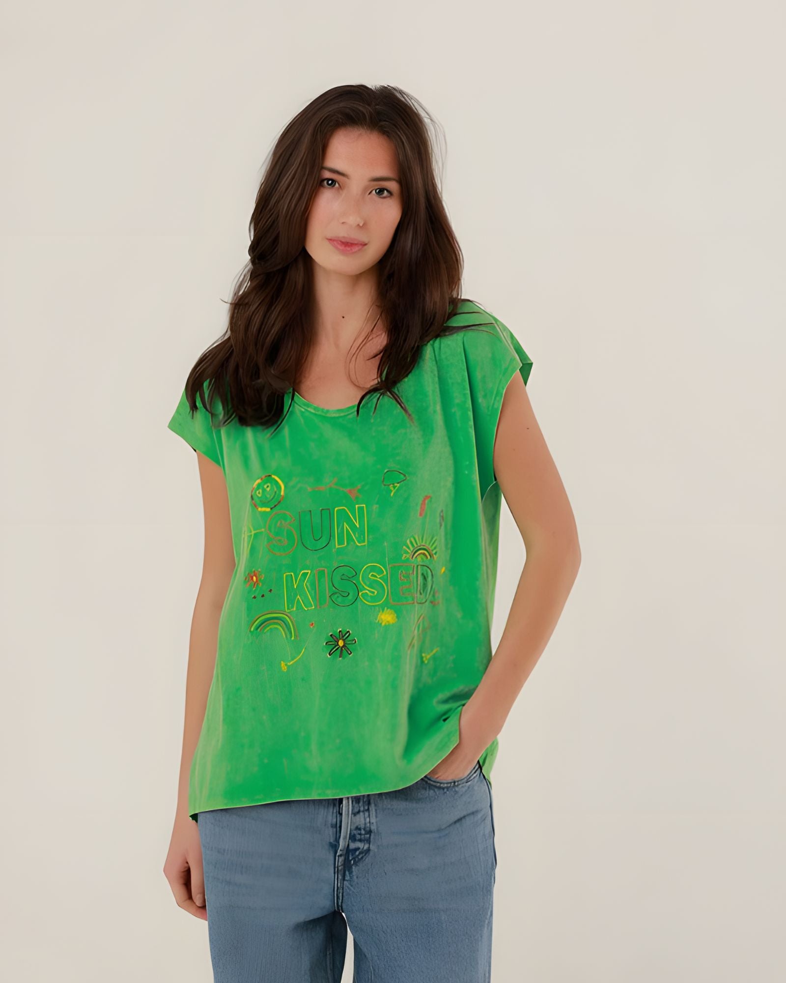 Close-up front view of a model wearing the vibrant green cotton Molly T-shirt with multicolored SUN KISSED chest embroidery.
