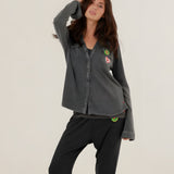 A woman wearing the charcoal carbone Tess fluid cotton-modal shirt featuring a straight cut and colorful patches, paired with matching sweatpants.