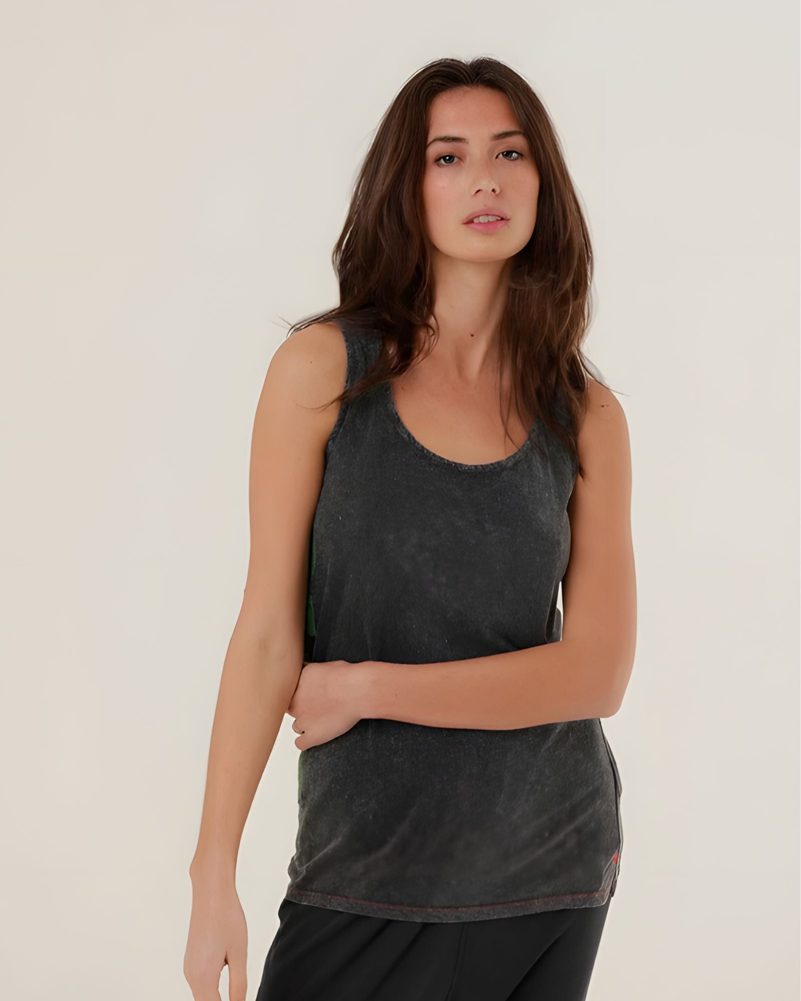 A mid-shot of a model wearing the charcoal carbone Top Mia tank top, highlighting the classic scoop neck and relaxed straight fit.