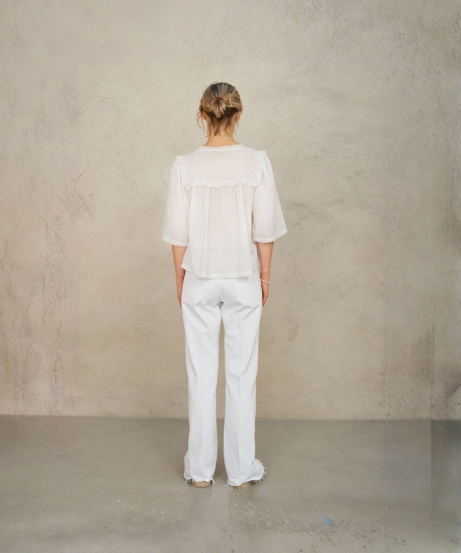 Back view of model wearing white lace cotton blouse by Mabe Apparel.