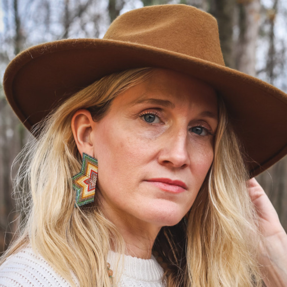 A woman wearing the Beaded Handwoven Large Half Star Earrings in Olive 
