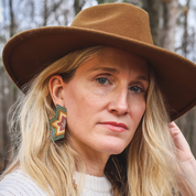 A woman wearing the Beaded Handwoven Large Half Star Earrings in Olive 