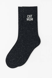 Close-up of black sparkly crew sock with white "CAT MUM" glitter text.
