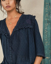 Close-up of the scalloped lace trim and floral embroidery on a Mabe Apparel navy blue blouse.