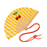 Close-up view of the opened yellow striped wooden fan, showcasing the vibrant cherry graphics, fabric texture, and attached red contrast cord.