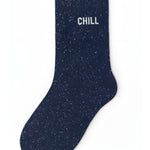 Deep navy blue glitter message socks with a white jacquard CHILL inscription at the ankle, presented in their original Woom paper packaging.
