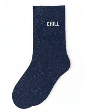 Deep navy blue glitter message socks with a white jacquard CHILL inscription at the ankle, presented in their original Woom paper packaging.