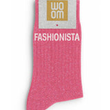 Vibrant pink glitter message socks with a white jacquard FASHIONISTA inscription at the ankle, presented in their original Woom paper packaging.