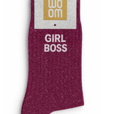 Rich wine-colored glitter message socks with a white jacquard GIRL BOSS inscription at the ankle, shown in their original Woom packaging.