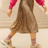 Close-up lifestyle shot of a model wearing the rose gold glitter message socks paired with a pleated gold skirt and casual sneakers.