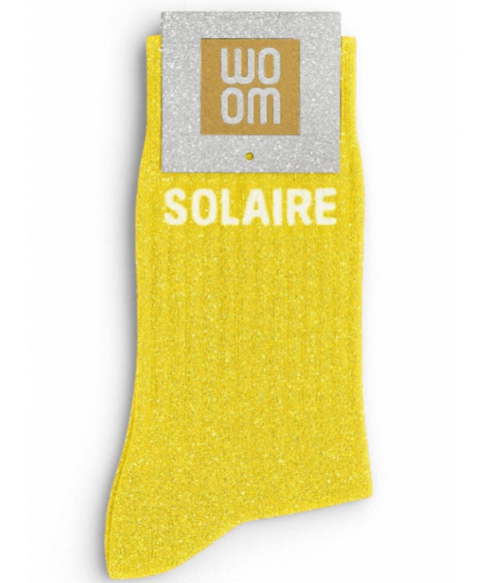 Vibrant yellow glitter message socks with a white jacquard SOLAIRE inscription at the ankle, presented in their original Woom paper packaging.