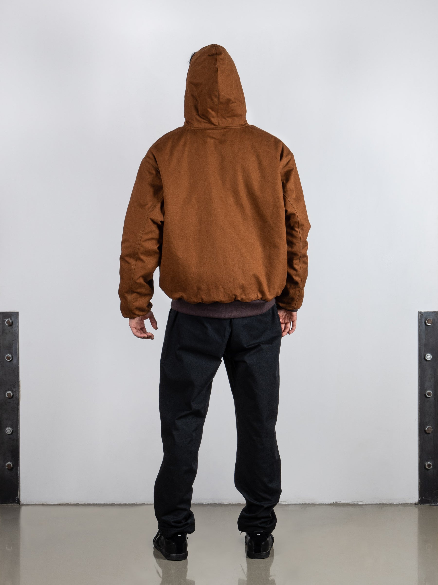 A man wearing a rust brown men's jacket by French Brand Crest. Rust Reversible Hooded Jacket with Italian padded cotton lining