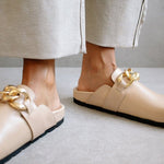Front view of both ALOHAS nude clogs worn on the feet, with the gold chain trim in focus.