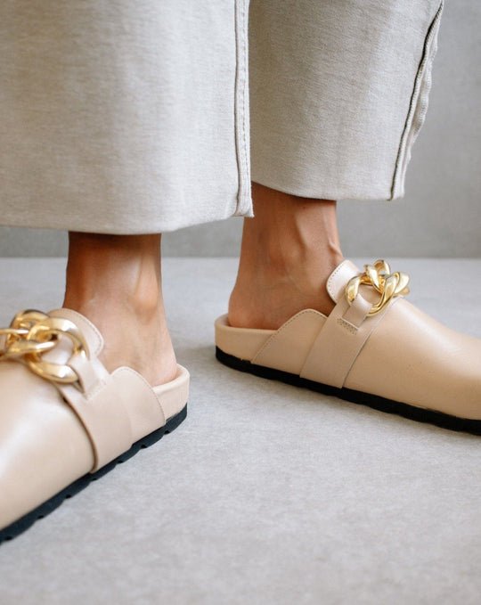 Front view of both ALOHAS nude clogs worn on the feet, with the gold chain trim in focus.