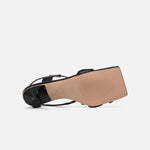 Underside view of the ALOHAS black square-toe slingback heels, showing the tan sole and sculpted heel.