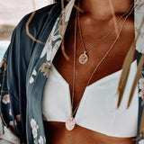 Model wearing the Azuni Astral All Seeing Eye pendant layered with other necklaces over a white top.