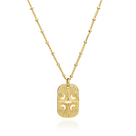 Azuni Astral ID Tag necklace, a gold rectangular tag engraved with a moon and stars on a beaded chain.