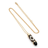 Azuni Black Lynx Totem necklace shown with its fine gold chain coiled on a white background.