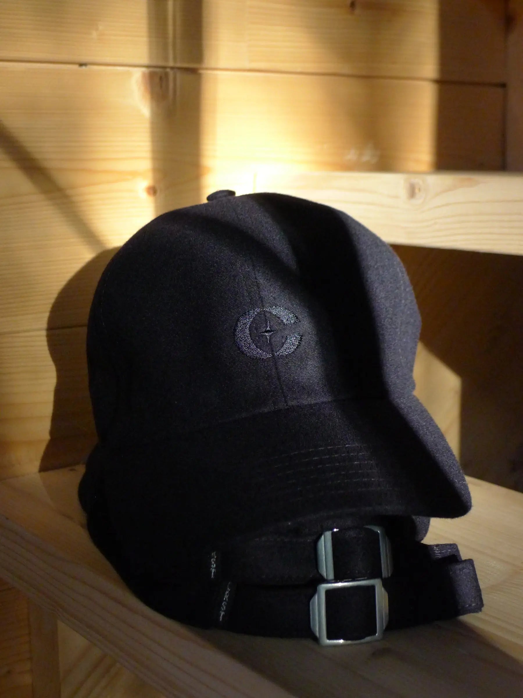 a black hat sitting on top of a wooden shelf