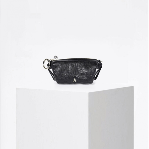 Craie Studio Doux wallet in black metallic leather with D-rings and a zip closure, on a plinth.
