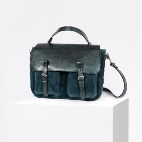Craie Studio Maths satchel in petrol corduroy with a leather flap, top handle and two pockets, on a plinth.