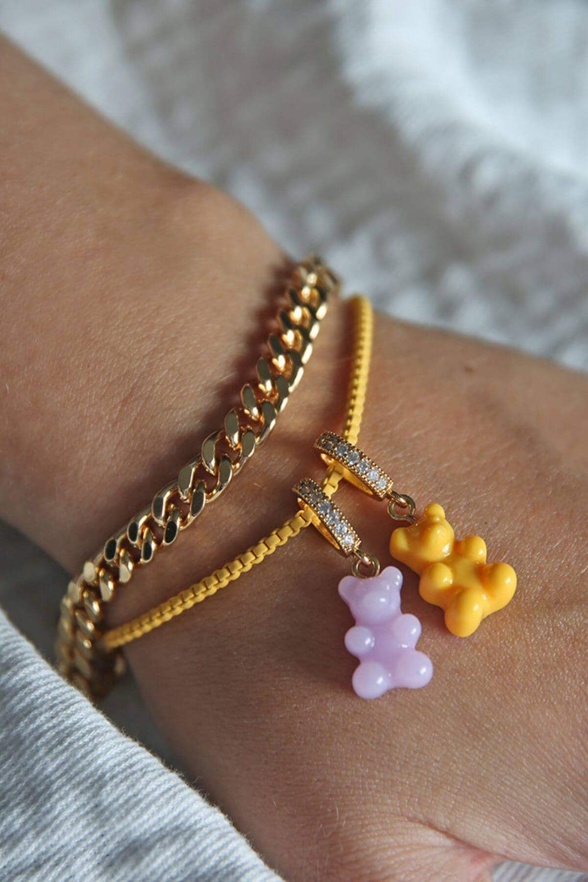 Crystal Haze yellow Nostalgia Bear charm shown stacked with a lavender charm on gold bracelets