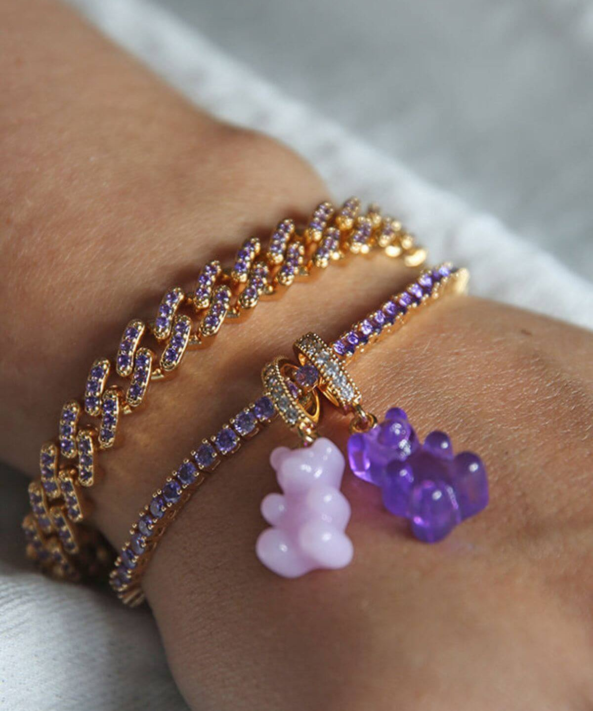 Crystal Haze purple Nostalgia Bear pendant worn on a bracelet stack, layered with a pink bear charm.