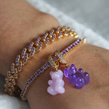 Crystal Haze purple Nostalgia Bear pendant worn on a bracelet stack, layered with a pink bear charm.