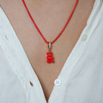 Crystal Haze red Nostalgia Bear pendant worn on a thin red cord necklace, resting at the collarbone.