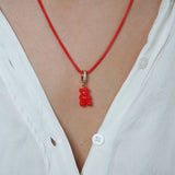 Crystal Haze red Nostalgia Bear pendant worn on a thin red cord necklace, resting at the collarbone.