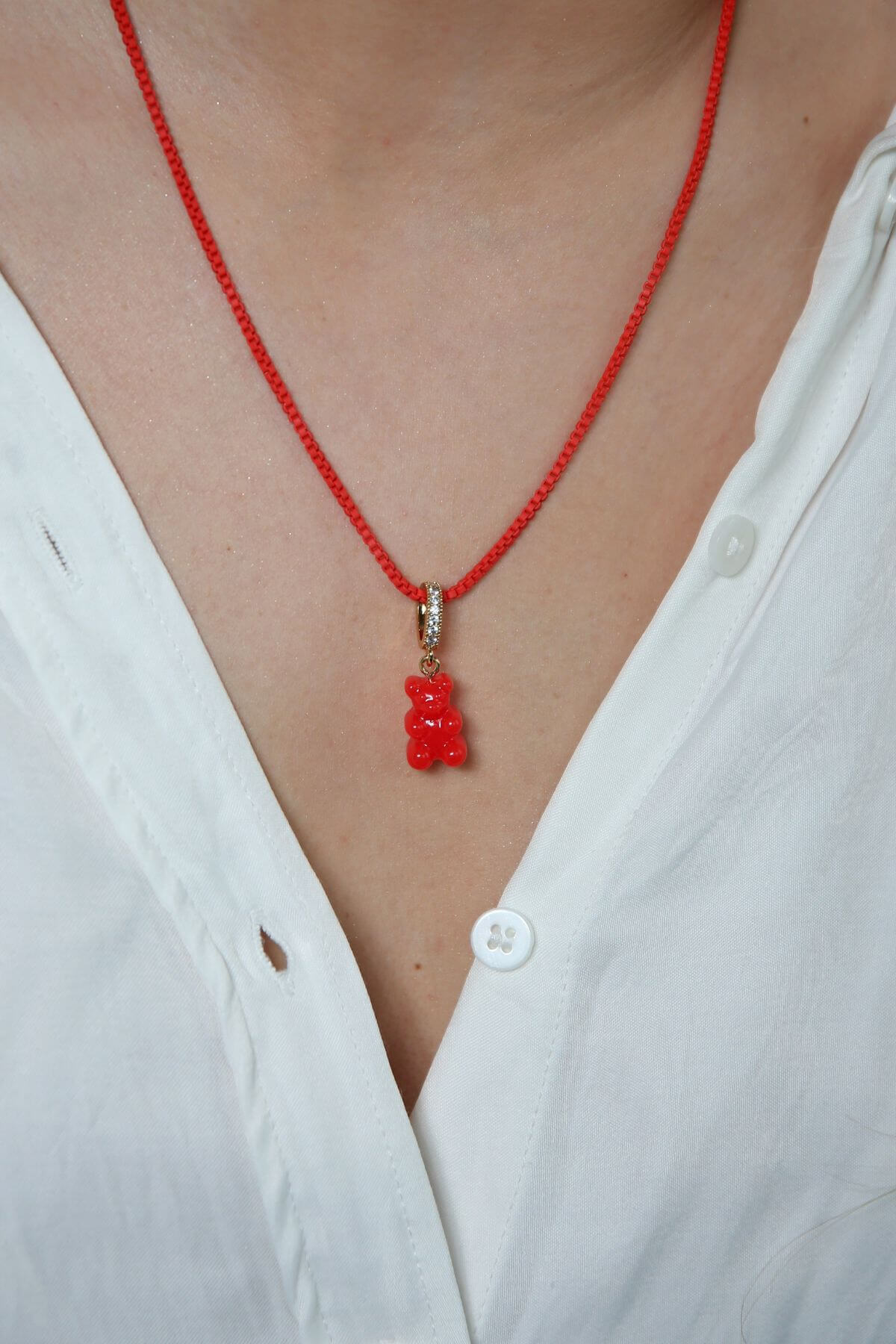 Crystal Haze red Nostalgia Bear pendant worn on a thin red cord necklace, resting at the collarbone.
