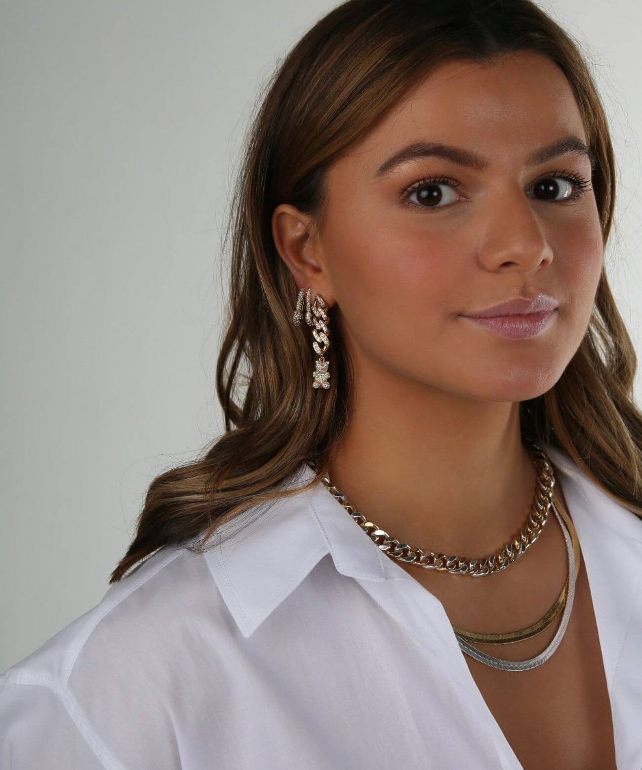 Model wearing the Crystal Haze Pavé Nostalgia gold earring layered with hoops and a chain necklace.