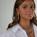 Model wearing the Crystal Haze Pavé Nostalgia gold earring layered with hoops and a chain necklace.