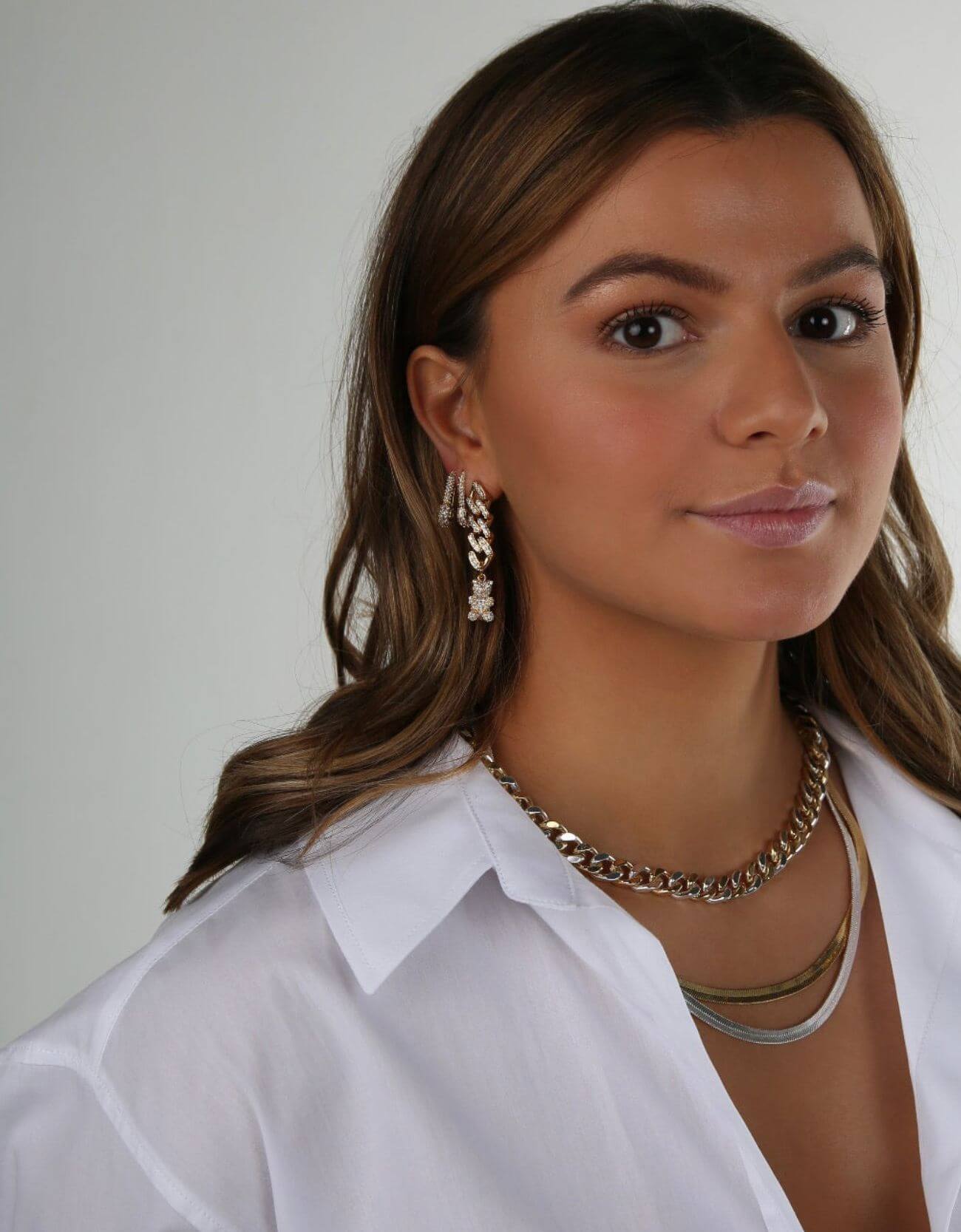 Model wearing the Crystal Haze Pavé Nostalgia gold earring layered with hoops and a chain necklace.