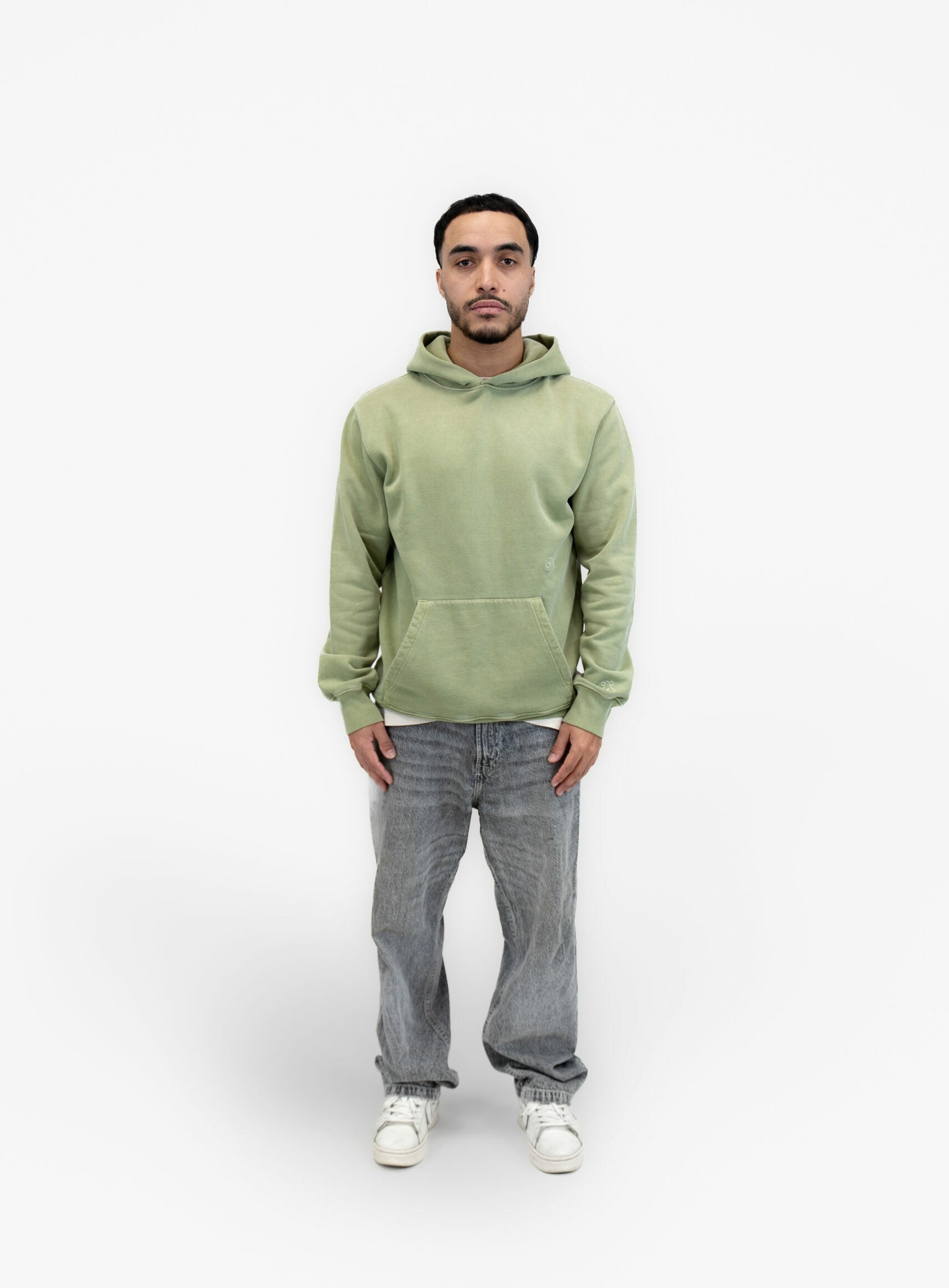A model wearing the green mineral dyed organic hoodie by French Sustainable Menswear Brand DOXA.