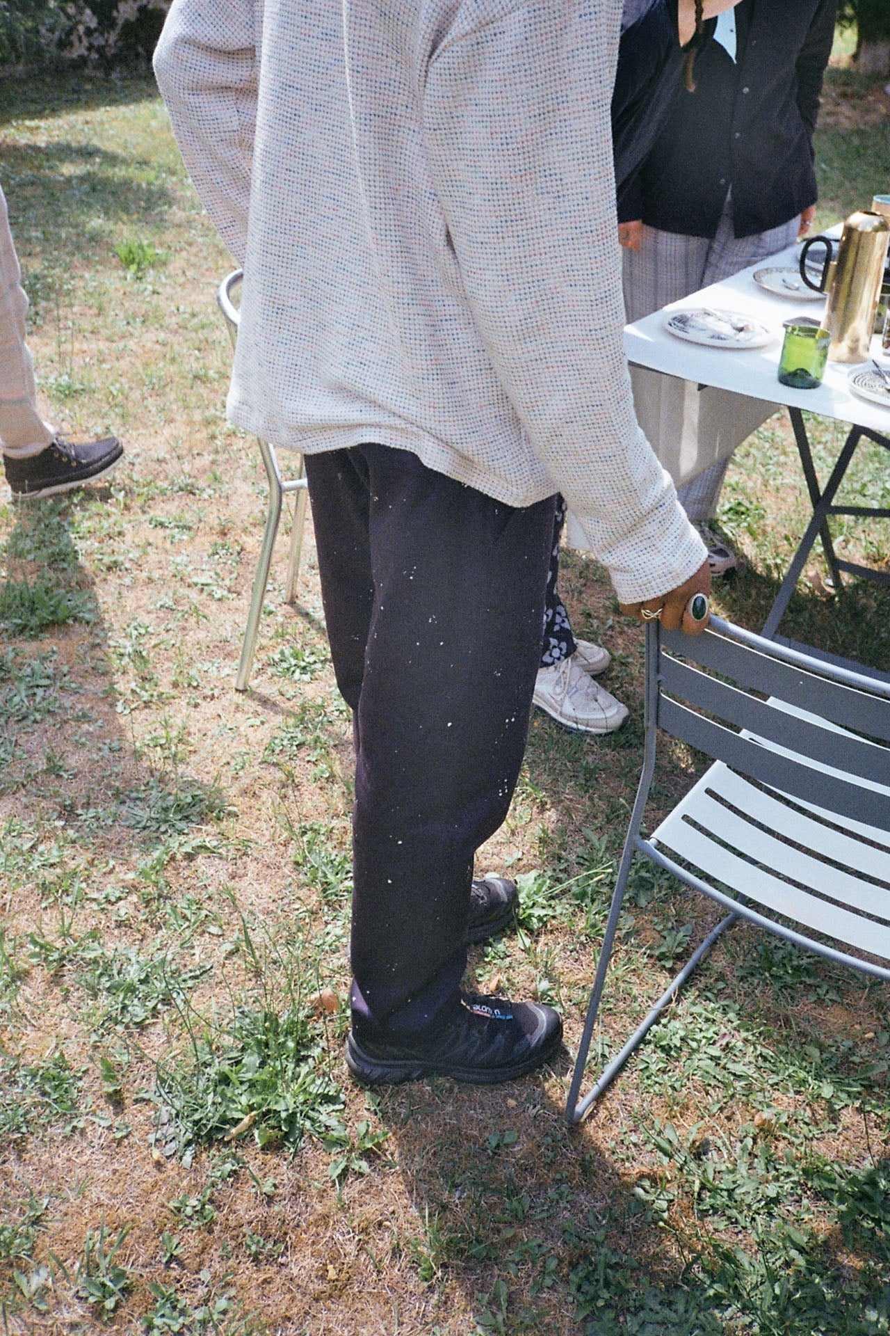 A person standing next to a chair in a field wearing the hand-painted easy pants with two slanted and welt pockets by French Brand Crest-