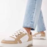 Woman wearing the Nubikk Buxton Basket sand sneakers with cropped blue jeans, street-style shot.